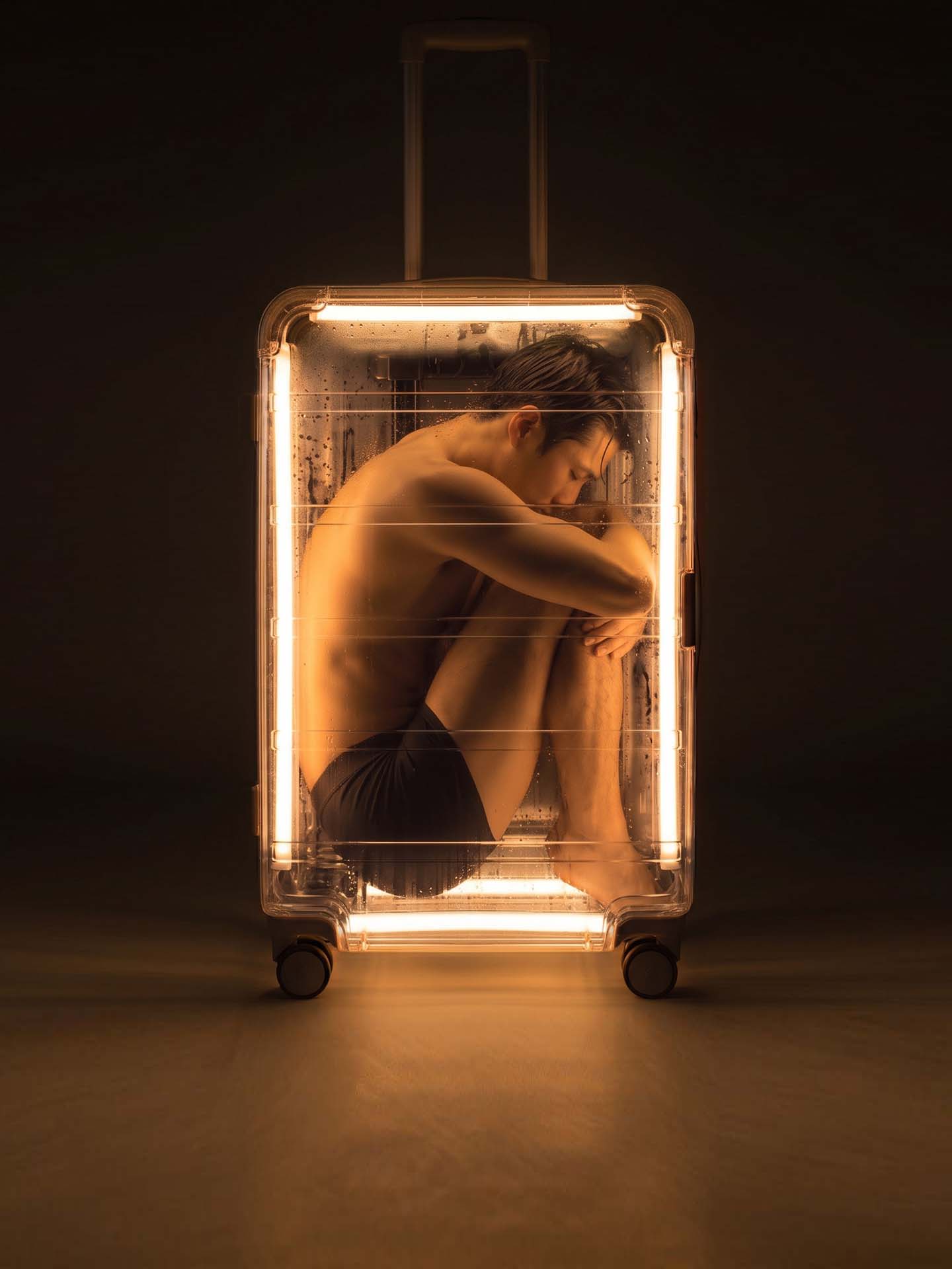 A figure curled inside a glowing suitcase, from the “Where Am I From” concept art